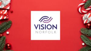 The Vision Norfolk logo on a red background with presents, evergreen needles, baubles, and candy canes around the edge of the image.