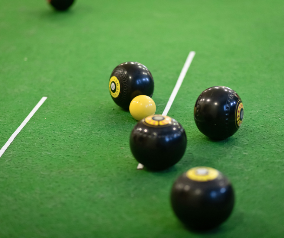 Black and white bowls balls on the green mat.