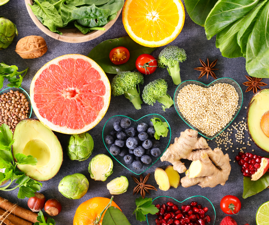 Colourful fruits, vegetables, grains and spices laid out on a dark table. Some of the food is in heart shaped bowls.